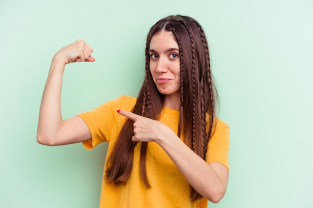 女性の力の腕のシンボルと強さのジェスチャーを示す緑の背景に分離された若い白人女性