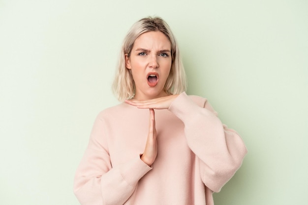 Young caucasian woman isolated on green background showing a timeout gesture.