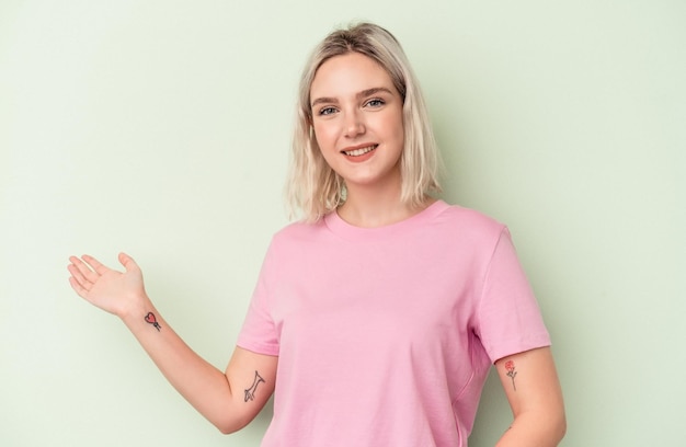 Young caucasian woman isolated on green background showing a welcome expression.