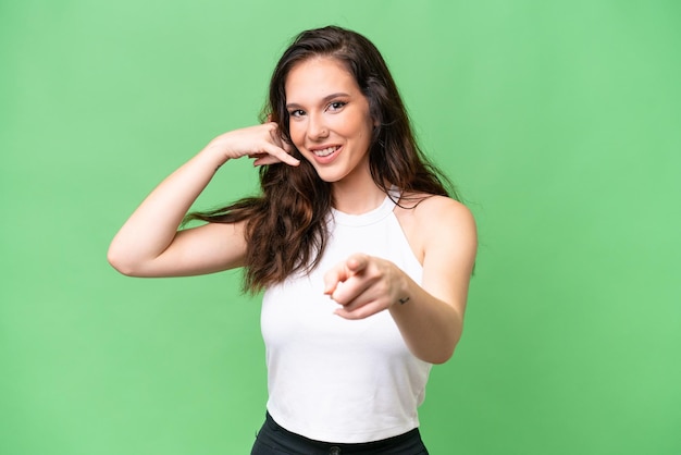 Young caucasian woman isolated over isolated background making phone gesture and pointing front