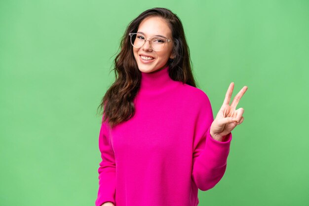 Young caucasian woman isolated over isolated background smiling and showing victory sign