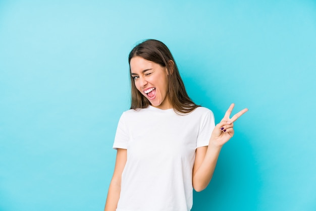 Young caucasian woman  isolated joyful and carefree showing a peace symbol with fingers.