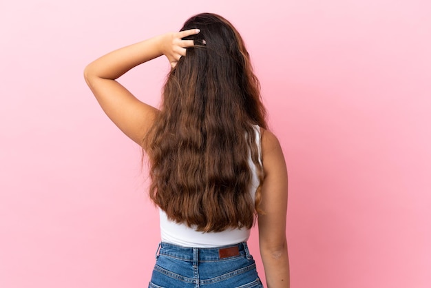 Young caucasian woman isolated on pink background in back position and thinking