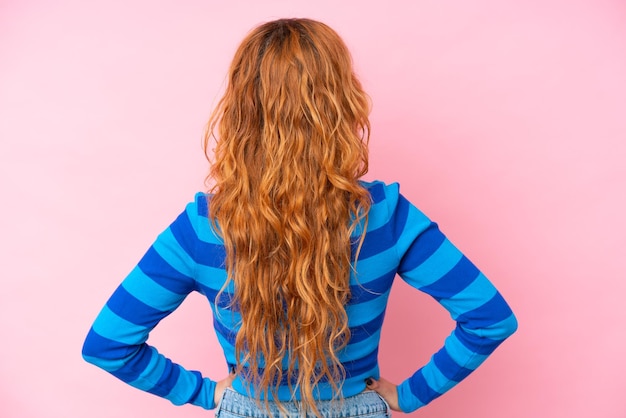 Young caucasian woman isolated on pink background in back position