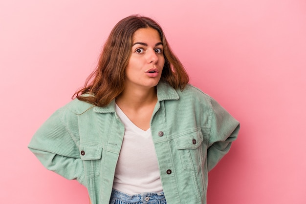 Young caucasian woman isolated on pink background  being shocked because of something she has seen.