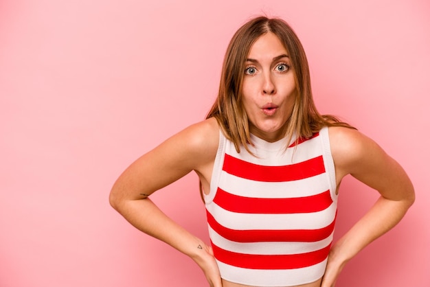 Young caucasian woman isolated on pink background being shocked because of something she has seen