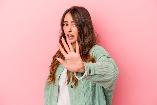 Young caucasian woman isolated on pink background being shocked due to an imminent danger
