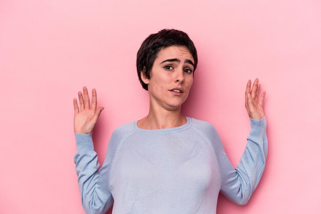 Photo young caucasian woman isolated on pink background being shocked due to an imminent danger