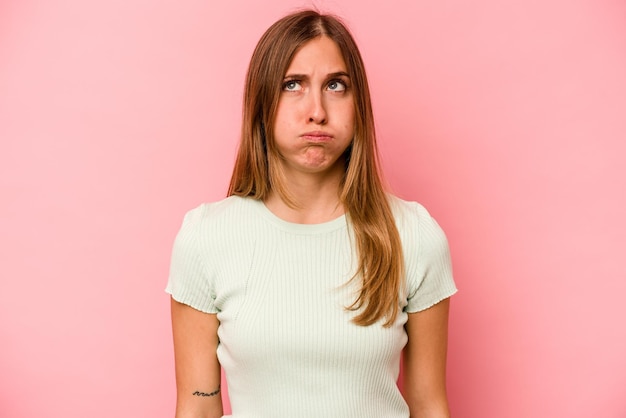 Young caucasian woman isolated on pink background blows cheeks has tired expression Facial expression concept