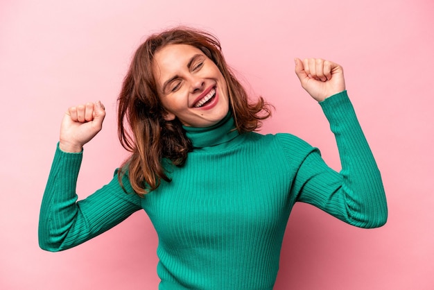 Young caucasian woman isolated on pink background celebrating a special day jumps and raise arms with energy