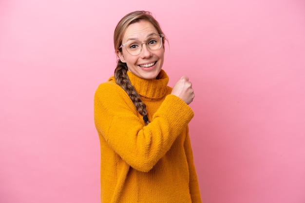 Young caucasian woman isolated on pink background celebrating a victory