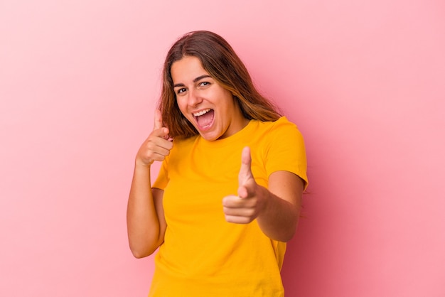 Young caucasian woman isolated on pink background  cheerful smiles pointing to front.
