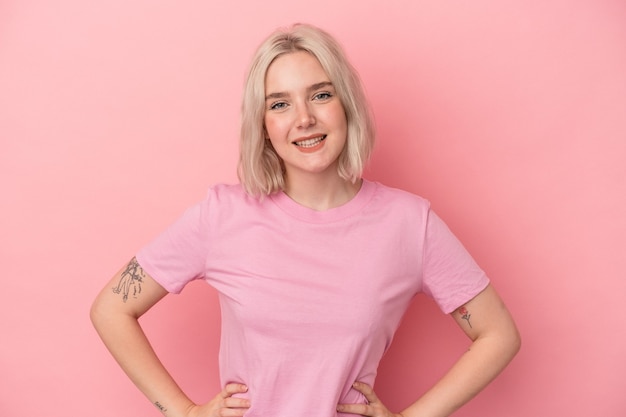 Photo young caucasian woman isolated on pink background confident keeping hands on hips.