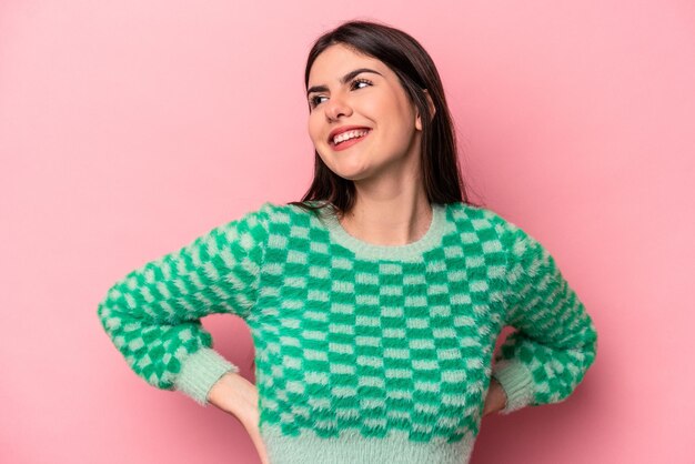 Young caucasian woman isolated on pink background confident keeping hands on hips