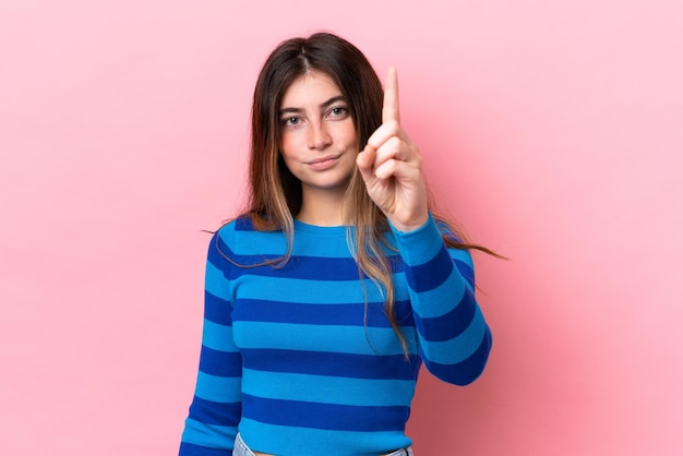 Photo young caucasian woman isolated on pink background counting one with serious expression