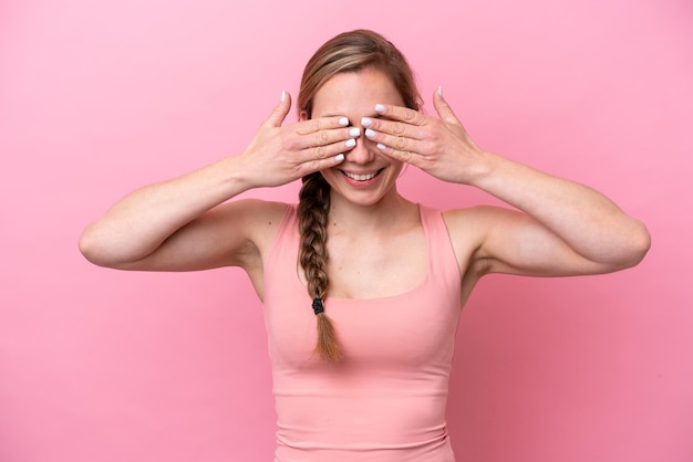 Young caucasian woman isolated on pink background covering eyes by hands and smiling