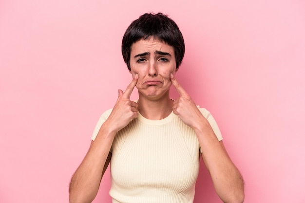 Young caucasian woman isolated on pink background crying, unhappy with something, agony and confusion concept.