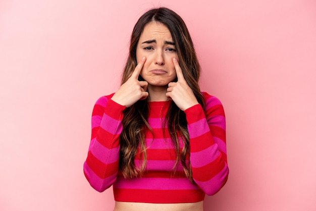 Young caucasian woman isolated on pink background crying unhappy with something agony and confusion concept