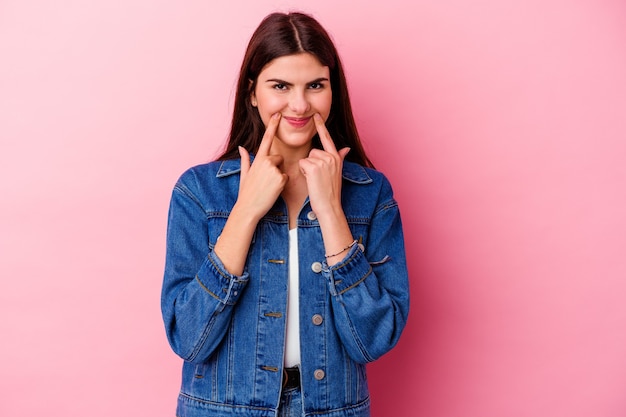 Young caucasian woman isolated on pink background doubting between two options.