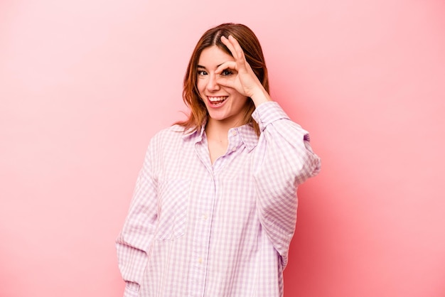 Young caucasian woman isolated on pink background excited keeping ok gesture on eye