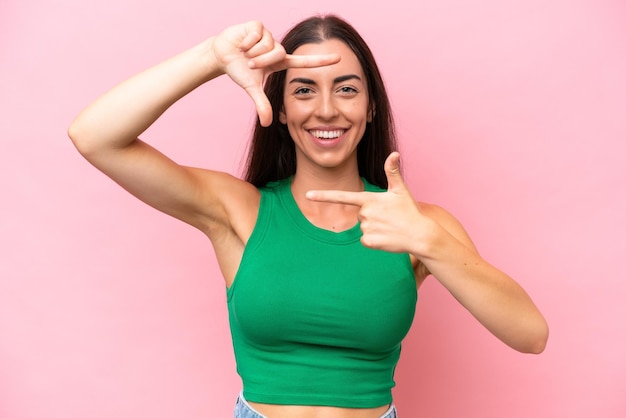 Giovane donna caucasica isolata su sfondo rosa che si concentra sul viso simbolo di inquadratura