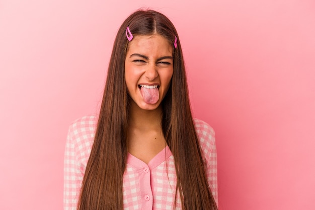 Young caucasian woman isolated on pink background funny and friendly sticking out tongue.