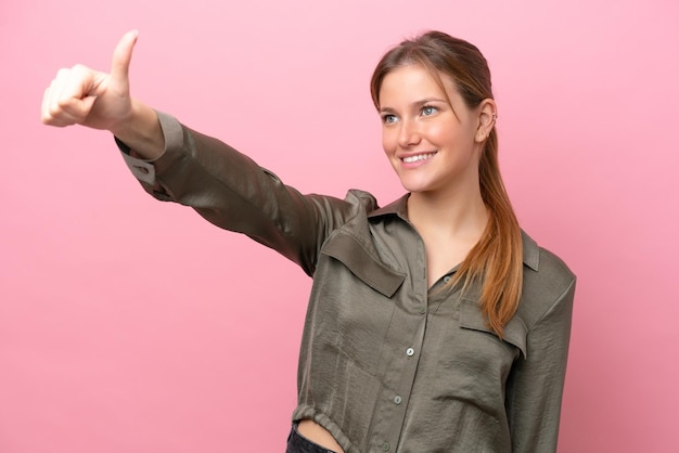 Young caucasian woman isolated on pink background giving a thumbs up gesture