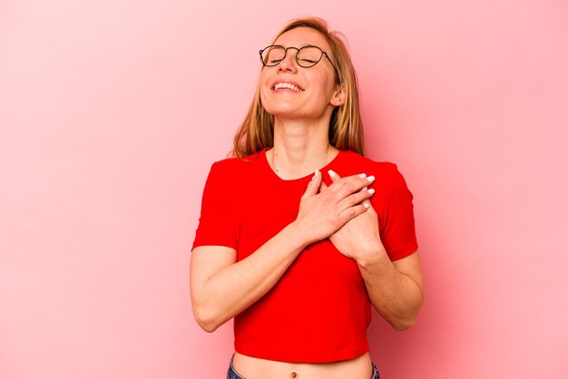 Young caucasian woman isolated on pink background has friendly expression pressing palm to chest Love concept