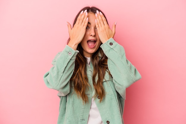 Young caucasian woman isolated on pink background having fun covering half of face with palm.