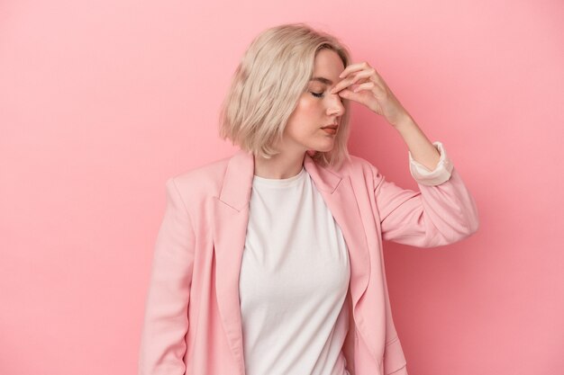 Young caucasian woman isolated on pink background having a head ache, touching front of the face.