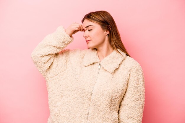 Young caucasian woman isolated on pink background having a head ache touching front of the face