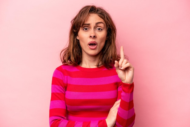 Young caucasian woman isolated on pink background having some great idea concept of creativity