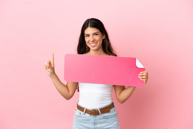 Young caucasian woman isolated on pink background holding an empty placard