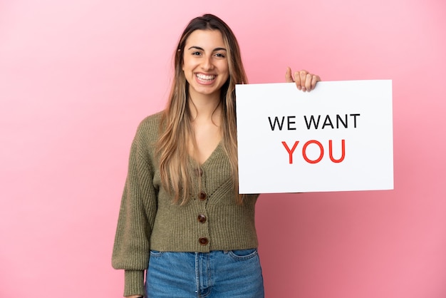 Photo young caucasian woman isolated on pink background holding we want you board with happy expression