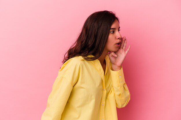 Young caucasian woman isolated on pink background is saying a secret hot braking news and looking aside