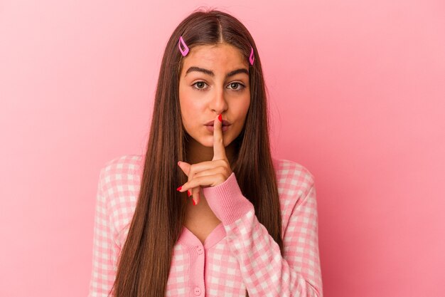 Photo young caucasian woman isolated on pink background keeping a secret or asking for silence.