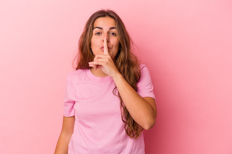 Photo young caucasian woman isolated on pink background  keeping a secret or asking for silence.