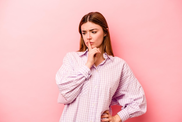 Young caucasian woman isolated on pink background keeping a secret or asking for silence