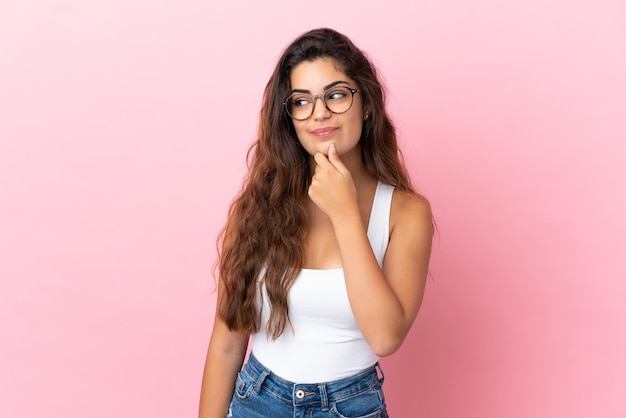 Young caucasian woman isolated on pink background and looking up