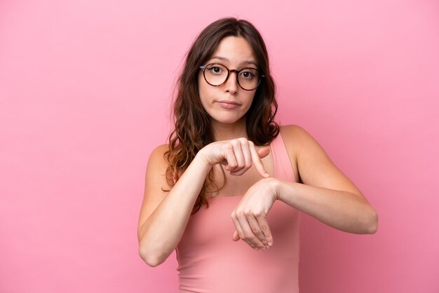 Young caucasian woman isolated on pink background making the gesture of being late