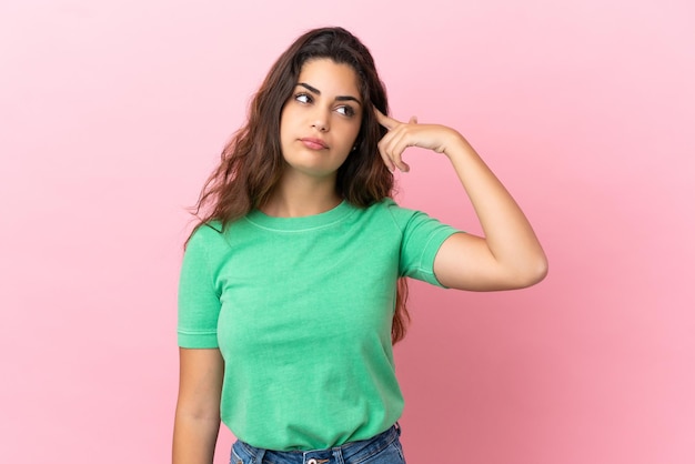 Young caucasian woman isolated on pink background making the gesture of madness putting finger on the head