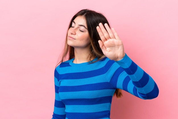 Young caucasian woman isolated on pink background making stop gesture and disappointed