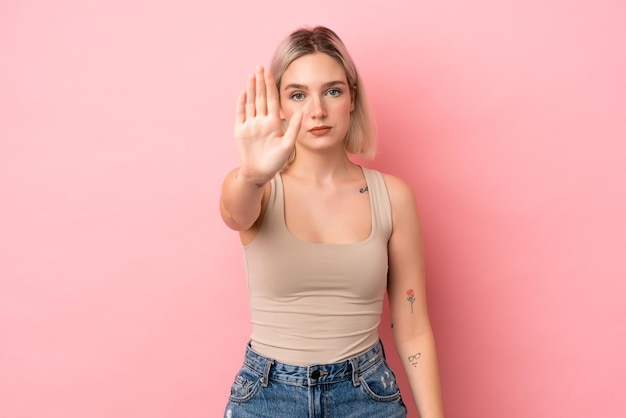 Young caucasian woman isolated on pink background making stop gesture