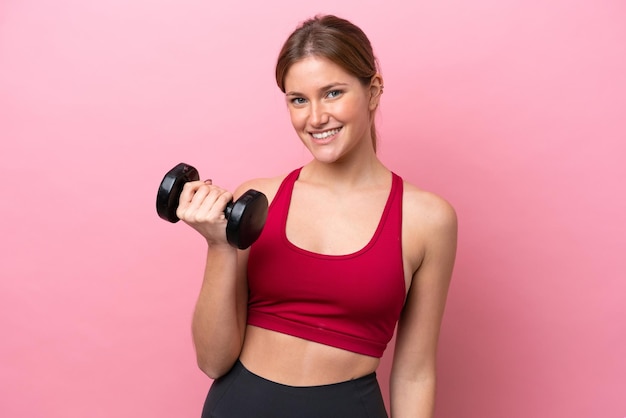 Young caucasian woman isolated on pink background making weightlifting