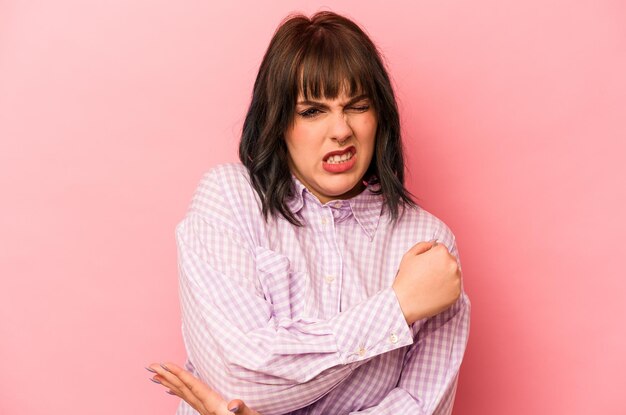 Young caucasian woman isolated on pink background massaging elbow suffering after a bad movement