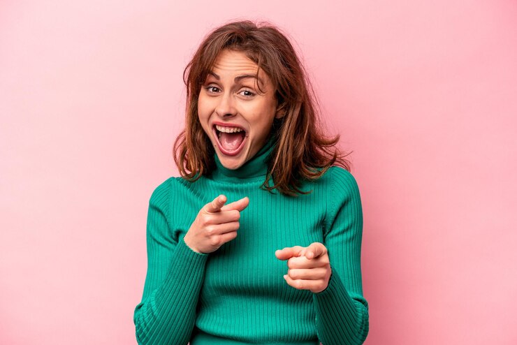 Photo young caucasian woman isolated on pink background pointing to front with fingers