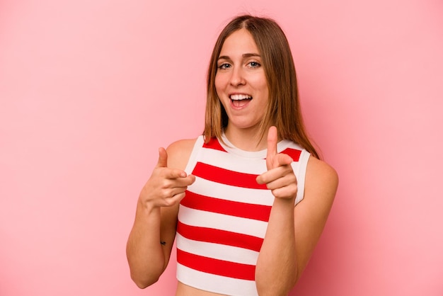 Young caucasian woman isolated on pink background pointing to front with fingers