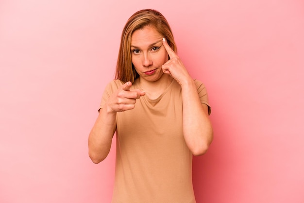 Young caucasian woman isolated on pink background pointing temple with finger thinking focused on a task