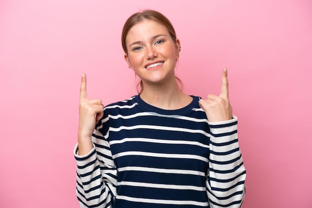 Young caucasian woman isolated on pink background pointing up a great idea