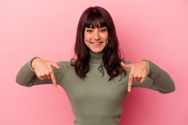 Young caucasian woman isolated on pink background points down with fingers, positive feeling.